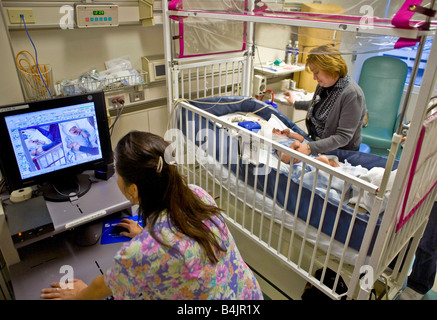 Bébé garçon dans un hôpital de Californie souffre de la colonne vertébrale bifida portant une électrode EEG est rempli avec maman et travailleur social Banque D'Images