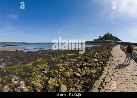 Jeune couple promenade le long de St Michaels Mount Causeway, à la fin de l'été soleil Cornwall Marazion West Country England UK GO Banque D'Images