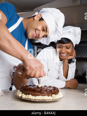 Hispanic male pastry chef decorating cake Banque D'Images