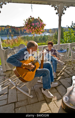 Le guitariste d'âge moyen joue pour son épouse la jouissance sous le porche d'une maison de campagne dans le Michigan aux couleurs de l'automne de presse Banque D'Images