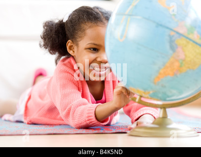 Mixed Race girl looking at globe Banque D'Images
