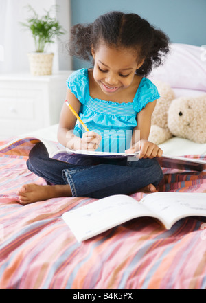 Mixed Race girl fait ses devoirs dans la chambre Banque D'Images