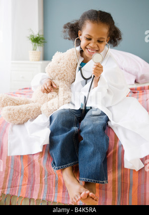 Mixed Race girl playing doctor avec ours Banque D'Images