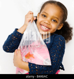 Mixed Race girl holding goldfish dans un sac Banque D'Images