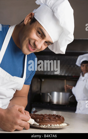 Hispanic male pastry chef decorating cake Banque D'Images