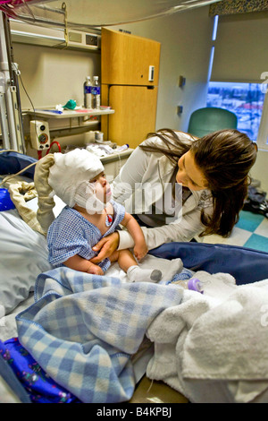 Dans un hôpital de Californie une mère prend soin de son bébé souffrant de moelle bifida Remarque condition monitoring EEG cap Banque D'Images