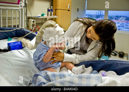 Dans un hôpital de Californie une mère prend soin de son bébé souffrant de moelle bifida Remarque condition monitoring EEG cap Banque D'Images