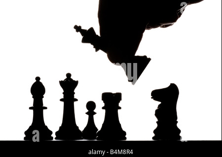 Main mâle déménagement pièces des échecs silhouetté sur chess board Banque D'Images