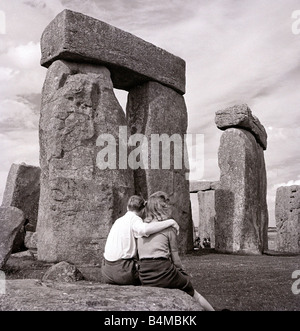 L'un des plus célèbres de Grande-Bretagne et mystérieux Stonehenge monuments anciens dans la plaine de Salisbury Wiltshire un jeune couple qui regarde le monument druidique où les pèlerins viennent pour adorer au solstice d'été Banque D'Images