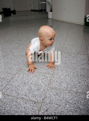 1 ans enfant explore la salle de séjour avec des meubles blancs et un sol en granit Banque D'Images