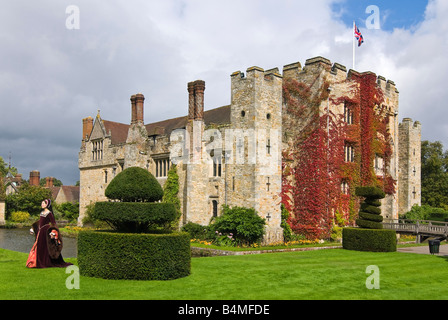 Grand angle horizontal de l'extérieur du château de Hever avec une dame habillée en Anne Boleyn marcher à l'extérieur, au soleil. Banque D'Images