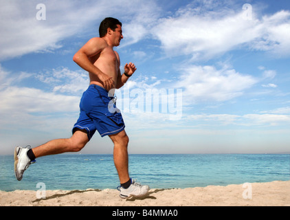 Jeune homme qui court tout seul sur la plage Banque D'Images