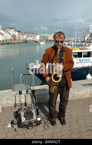 Saxaphone busker jouant sur le quai à Weymouth, dans le Dorset, Angleterre, RU Banque D'Images