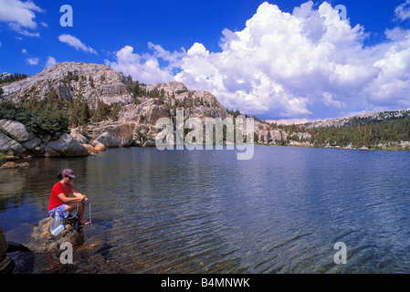 La purification de la femme l'eau potable sur la rive du lac Boothe Sierra Nevada Yosemite National Park California Banque D'Images