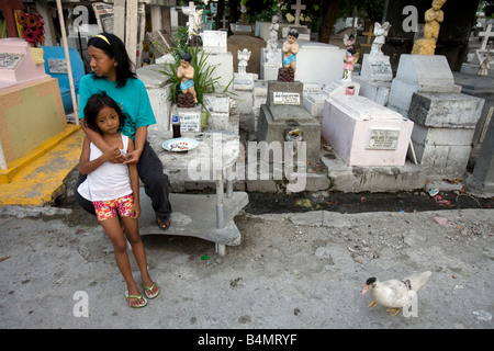 Une philippine et sa fille s'asseoir à l'extérieur de leur maison au cimetière de Makati City Makati City (Manille), Philippines. Banque D'Images