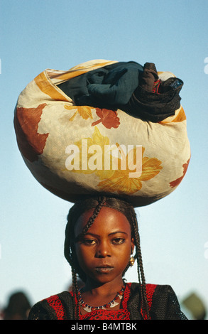 Le Niger, Agadez, désert du Sahara, fille de tribu touareg chiffon trasnporting on head Banque D'Images