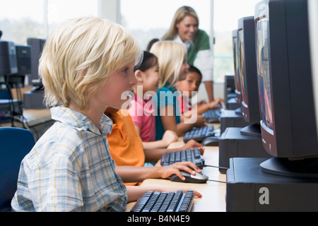 Les enfants devant un ordinateur avec l'enseignant en arrière-plan (profondeur de champ/high key) Banque D'Images