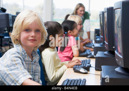 Les enfants devant un ordinateur avec l'enseignant en arrière-plan (profondeur de champ/high key) Banque D'Images