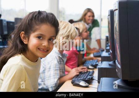 Les enfants devant un ordinateur avec l'enseignant en arrière-plan (profondeur de champ/high key) Banque D'Images