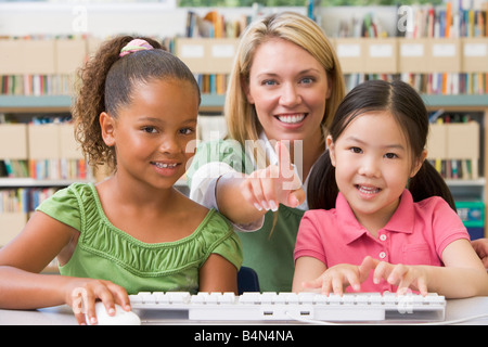 Deux étudiants en classe au clavier de l'ordinateur avec l'enseignant Banque D'Images