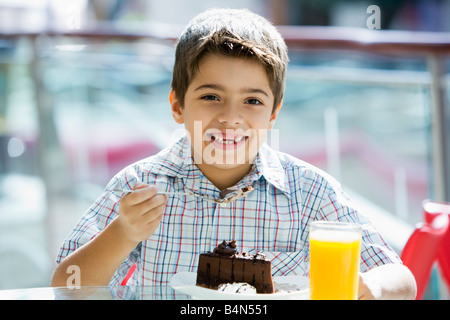 Jeune garçon au restaurant manger un dessert et smiling (selective focus) Banque D'Images