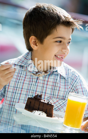 Jeune garçon au restaurant manger un dessert et smiling (selective focus) Banque D'Images