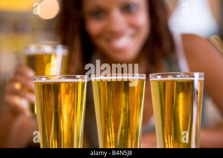 Femme posant avec plusieurs verres de bière Banque D'Images