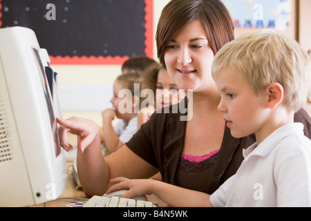 Étudiants en classe devant un ordinateur avec l'enseignant (selective focus) Banque D'Images