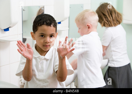 Les élèves dans la salle de bains à se laver les mains avec un puits holding up savonneux des mains (selective focus) Banque D'Images