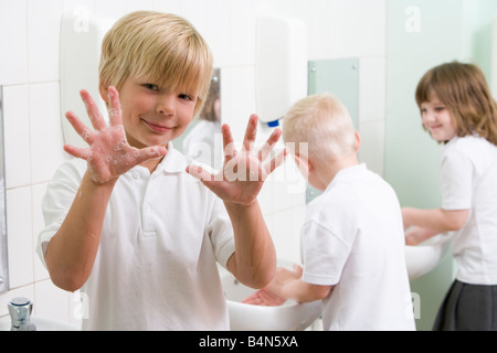 Les élèves dans la salle de bains à se laver les mains avec un puits holding up savonneux des mains (selective focus) Banque D'Images