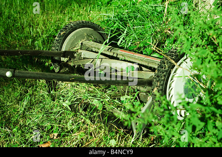 Tondeuse manuelle sur l'herbe en plein soleil avec l'accent sur les lames et avec des boutures de tondeuse. Banque D'Images