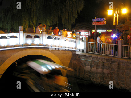 Voile passe sous le pont Yinding près du lac Houhai Lac Qianhai et dans le quartier de Shichahai de Pékin tandis que les touristes regarder Banque D'Images