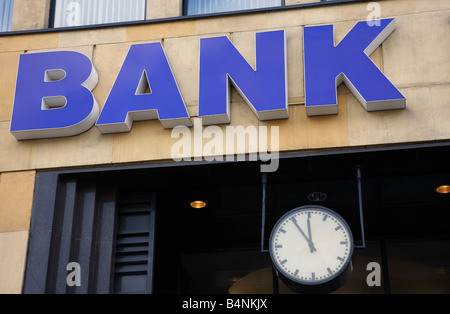 Signe de la banque sur un bâtiment et une horloge indiquant 5 à 12 Banque D'Images