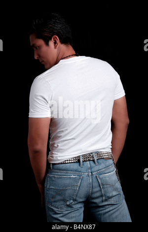 Portrait d'une jeune homme portant un t-shirt blanc et jean bleu, sur un fond noir Banque D'Images