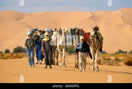 L'Algérie Djanet hommes de tribu touareg caravane de chameaux et deux touristes désert du Sahara Banque D'Images