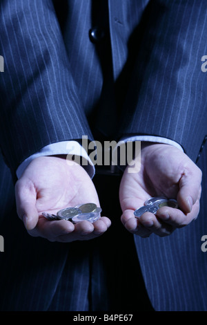 Businessman holding coins en main, mid section Banque D'Images