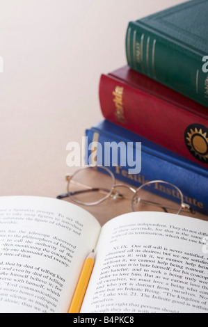 Crayon sur le livre ouvert avec les verres et pile de livres à proximité Banque D'Images