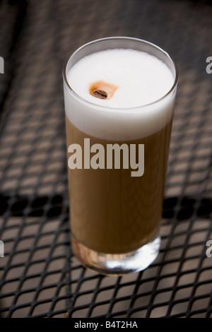 Un grand verre de cappuccino sur une table en fer forgé. Banque D'Images