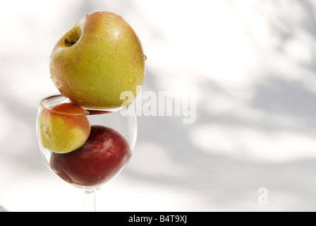 Verre de vin contenant de l'eau et divers fruits en pleine lumière Banque D'Images