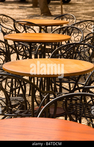 Café à l'extérieur avec des tables en bois vide circulaire recouvert d'acier et chaises dans une rangée Banque D'Images