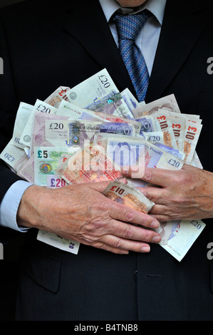 Homme d'affaires portant costume de bureau intelligent deux mains serrant piles UK livres sterling billets concept d'argent pour les banquiers gros chats cupidité hommes en costumes argent en main Banque D'Images