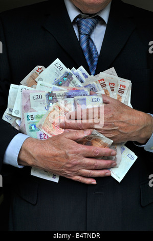 Homme portant un costume professionnel de bureau mains encombrant pile livre britannique espèces en monnaie la banque note un concept d'argent pour les banquiers gros chat cupidité par les hommes en costumes Banque D'Images