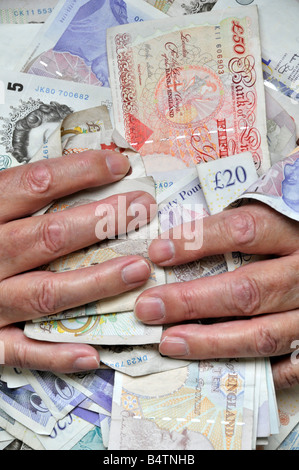 Pile de livres sterling bank notes tenues près de mans poitrine tourné en studio England UK Banque D'Images