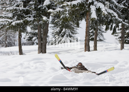 Femme couchée dans la neige avec des skis Banque D'Images