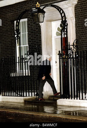 Londres 10 Downing Street avec vue arrière de Denis Thatcher portant un pantalon et veste chaussures brunes arrivant à l'entrée principale, marcher sur la porte avant l'étape avec une chaussée mouillée et freiner en premier plan Banque D'Images