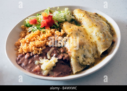 Enchiladas au poulet suisse rempli de crème sure et servi avec du riz et des haricots avec du fromage et salade hachée Banque D'Images