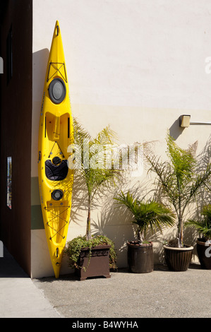 Un kayak jaune debout contre un mur blanc. Image de couleurs contrastées. Banque D'Images