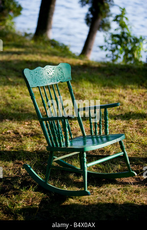 Une vieille chaise à bascule en bois à côté d'un lac à la fin de l'été. Banque D'Images