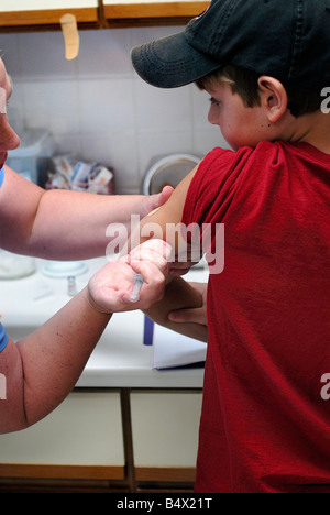 Garçon de 11 ans recevant la varicelle et vaccination de rappel des coups d'une infirmière dans un bureau de médecins Banque D'Images