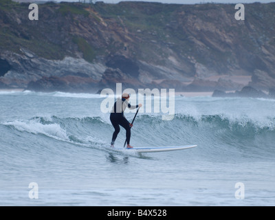 Un Stand Up Paddle Surfer en descendant une vague. Newquay, Cornwall Banque D'Images